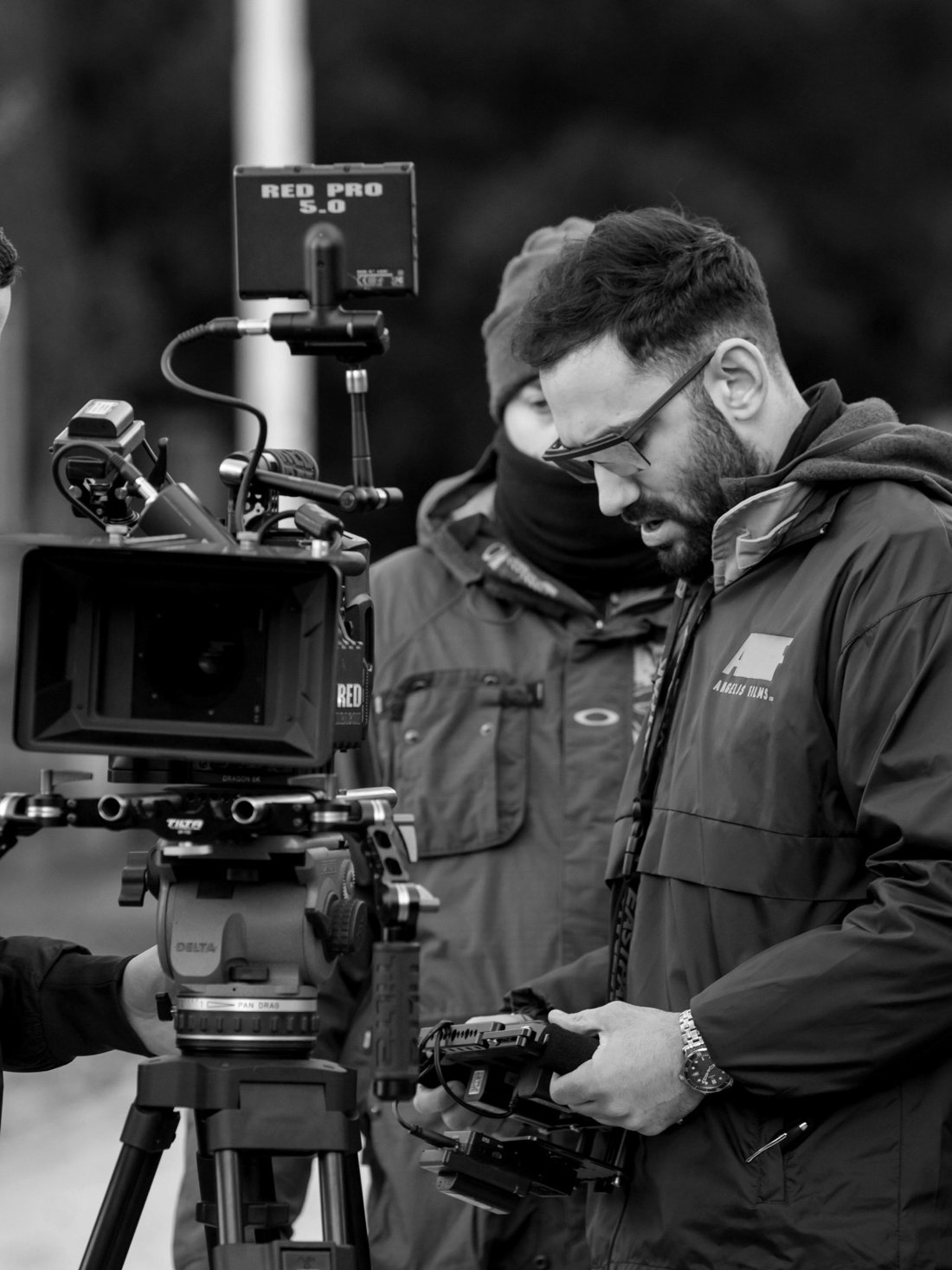 Thanos Angelis on set, checking a monitor beside a RED camera